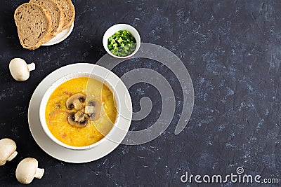 Champignon soup in a white bowl. Whole champignons, bread and cut green onions on a blue background. Stock Photo