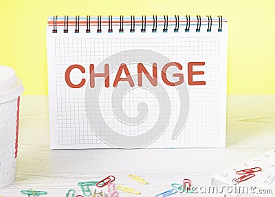 CHANGE the word is written on a blank sheet in a notebook standing on a table on a yellow background Stock Photo