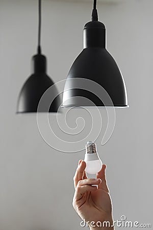 Changing the bulb for led bulb in floor lamp in black colour. On light gray background Stock Photo