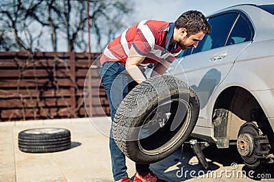 Changing a flat car tire in the backyard. Tire maintenance, damaged car tyre or changing seasonal tires Stock Photo