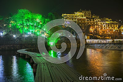 Small bamboo bridge in a river lead to an illumination lights FengHuang town at night in Changsha, China Editorial Stock Photo