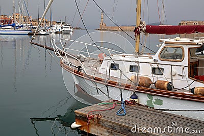 CHANIA, CRETE - MAY 29, 2014: The Venetian Outer Harbor with a sailing boat in the foreground Editorial Stock Photo