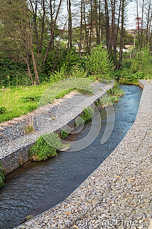 A channel made of granite stones for the river stream with grass and shrubs on the banks. Landscaping of the city, river Stock Photo