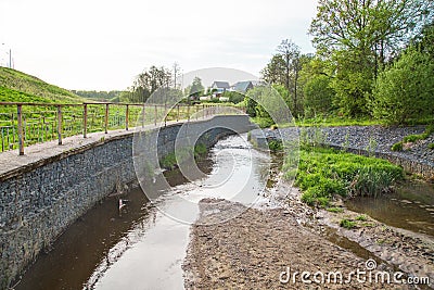 A channel made of granite stones for the river stream with grass and shrubs on the banks. Landscaping of the city, river Stock Photo