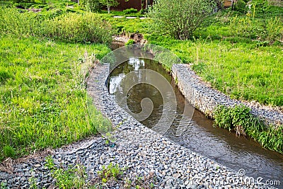 A channel made of granite stones for the river stream with grass and shrubs on the banks. Landscaping of the city, river Stock Photo