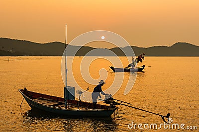 Chanthaburi, Thailand - February, 02, 2020 :Beautiful sunrise over sea with Silhouette of fishermen with yellow and orange sun in Stock Photo