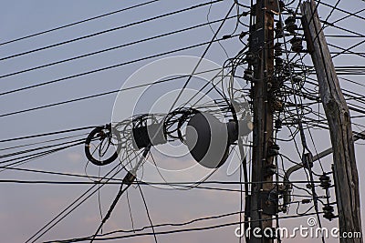 Chaotic Intertwining mess of electricity power lines on pole Stock Photo