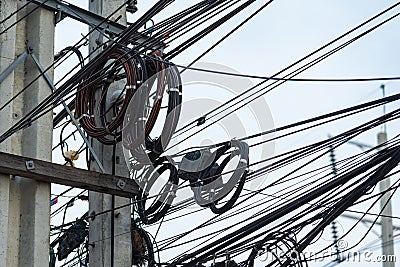 Chaotic Intertwining mess of electricity power lines on pole in Thailand Stock Photo