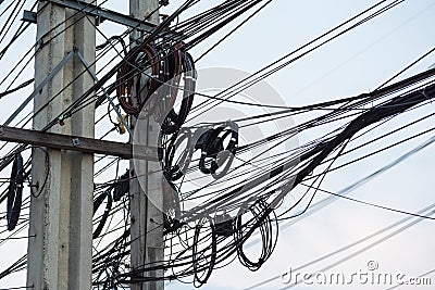 Chaotic Intertwining mess of electricity power lines on pole in Thailand Stock Photo