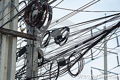 Chaotic Intertwining mess of electricity power lines on pole in Thailand Stock Photo