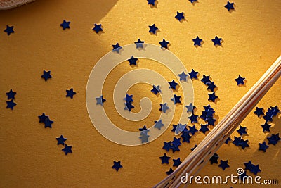 Chaotic located blue confetti little stars on a golden shimmer background. Celebration template. Flat lay. Top view Stock Photo