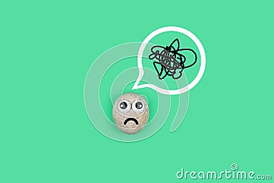 Character from a pebble with a sad face with a tangle of thoughts in its head. Character in search of ideas Stock Photo