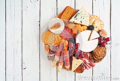 Charcuterie platter with different meats, cheeses and appetizers over a white wood Stock Photo