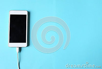 Close up white Smartphone Plug In with Charger Adapter on Blue Background Stock Photo