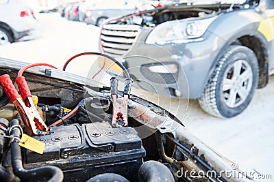 Charging automobile discharged battery by booster jumper cables at winter Stock Photo