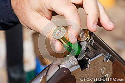 Charging a hunting rifle. Male hunter charges a double-barreled shotgun rounds Stock Photo