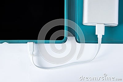 Charging tablet with power bank on white background Stock Photo