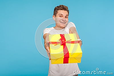 Charity and generosity. Kind happy man in white t-shirt giving gift box to camera and smiling Stock Photo