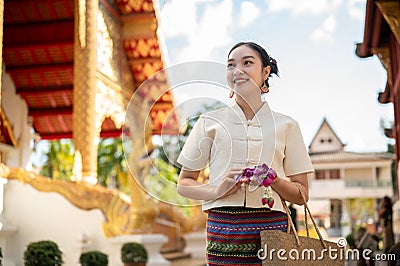 Charming Asian lady in a traditional Thai-Northern dress is visiting a temple on a Buddhist holy day Stock Photo