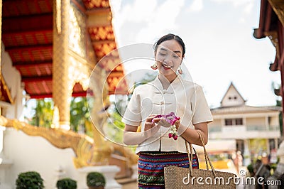 Charming Asian lady in a traditional Thai-Northern dress is visiting a temple on a Buddhist holy day Stock Photo