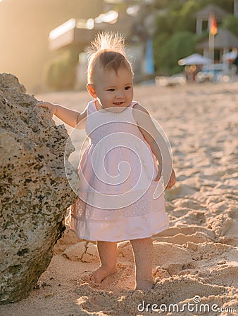 Charming girl in stylish dress on sandy beach with sunset tones Stock Photo