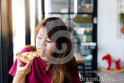 Charming beautiful asia woman enjoy eating yummy pizza and sticky mozzarella cheese. It has good taste. Pretty customer girl gets Stock Photo