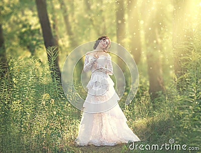 Charming beauty with dark hair standing in light forest, goddess and fairy of morning sun in warm rays, sweet girl in Stock Photo