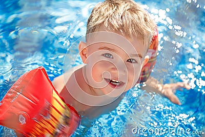 Charming blond boy bathes in a pool in the sleeves, laughing Stock Photo