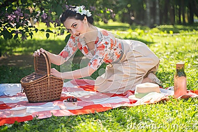 A charming brunette young girl enjoys a rest and a picnic on the green summer grass alone. pretty woman have a holiday and spend v Stock Photo