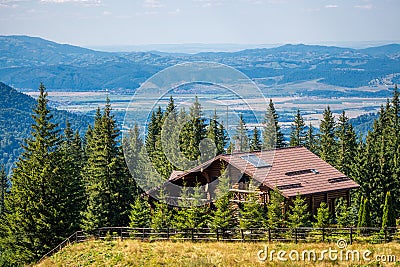 Charming cabin amidst the majestic mountains, standing tall above a lush green forest Stock Photo