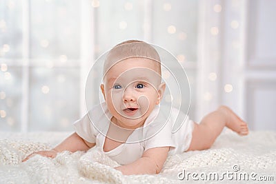 Charming cute baby is lying on the bed on a white blanket on a white background Stock Photo