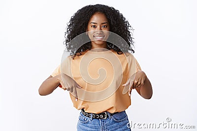 Charming cute lively young african-american 20s woman afro haircut smiling friendly pointing index fingers down bottom Stock Photo