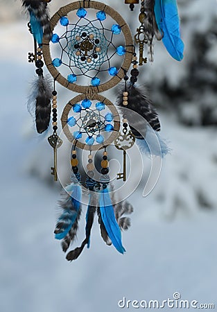 Charming decoration of dreamcatcher with blue feathers and key agains snow landscape. Stock Photo