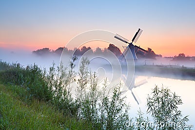 Charming Dutch windmill by river Stock Photo