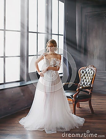 Charming excellent lady became bride, girl with blond gathered hair tries on wedding chic white luxurious light dress in Stock Photo