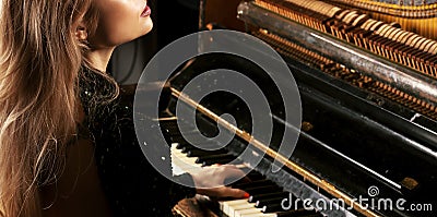 Charming girl in a green dress enjoys playing the retro piano Stock Photo