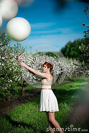 Charming girl holding white balloons looking sadly at them Stock Photo