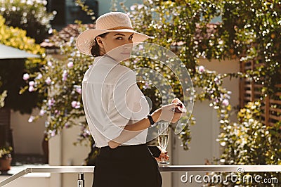 Charming girl is standing in the garden with a glass of champagne and a peach. The concept of vacation, travel, a country house Stock Photo