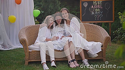 Charming happy pregnant woman and girls sitting on couch on backyard celebrating baby shower party. Wide shot smiling stock video footage Charming happy pregnant woman and girls sitting on couch on backyard celebrating baby shower party. Wide shot smiling stock video footage