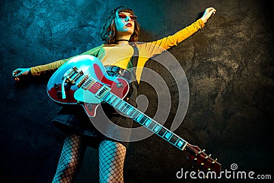 Charming hipster woman with curly hair with red guitar in neon lights. Rock musician is playing electrical guitar. 90s Stock Photo