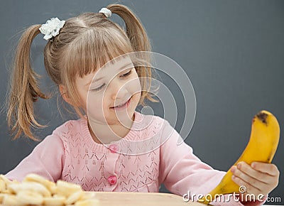 Charming little girl holding a ripe banana Stock Photo