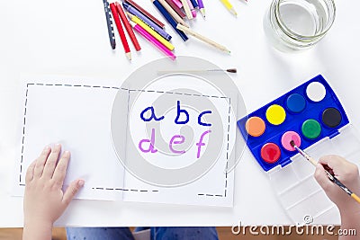 Charming little girl painting using watercolors.. Top view. Girl learning alphabet Stock Photo