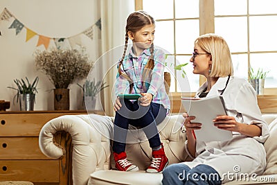 Charming pediatrician making notes during a conversation with sick child Stock Photo