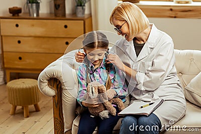 Charming physician giving a sick girl stethoscope to try on Stock Photo