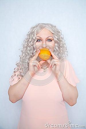 Charming plump curly blonde in pink dress with orange on white solid studio background alone Stock Photo
