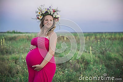 Charming pregnant woman with a wreath in the field Stock Photo