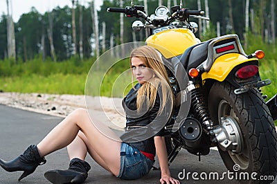 Charming woman biker sitting on asphalt with motorcycle Stock Photo