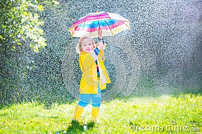 Charming toddler with umbrella playing in the rain Stock Photo