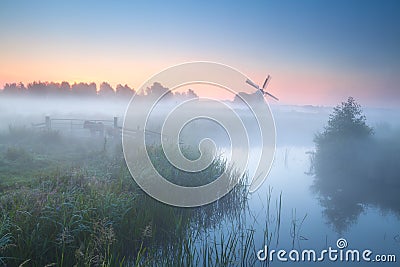 Charming windmill by misty river Stock Photo