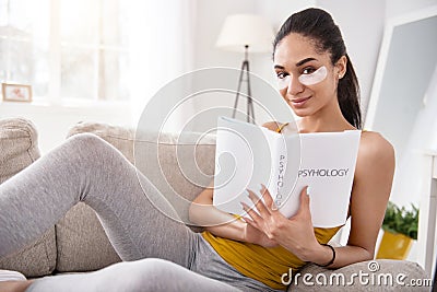 Charming woman posing with psychology book on couch Stock Photo